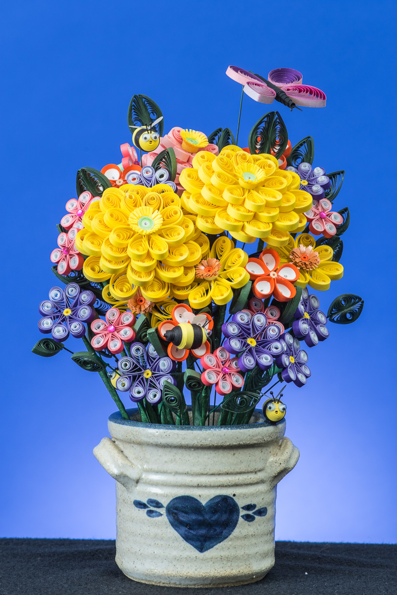 Flowers in a vase with bees and a butterfly.