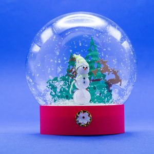 Plastic globe. Snowman, trees and playful reindeer are made from paper. Snow is synthetic flakes.