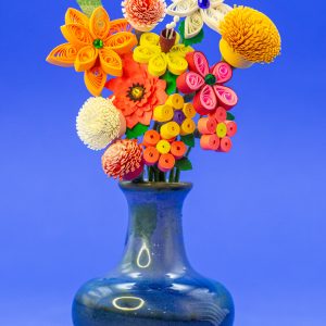 Blue ceramic vase of quilled and punched flowers.