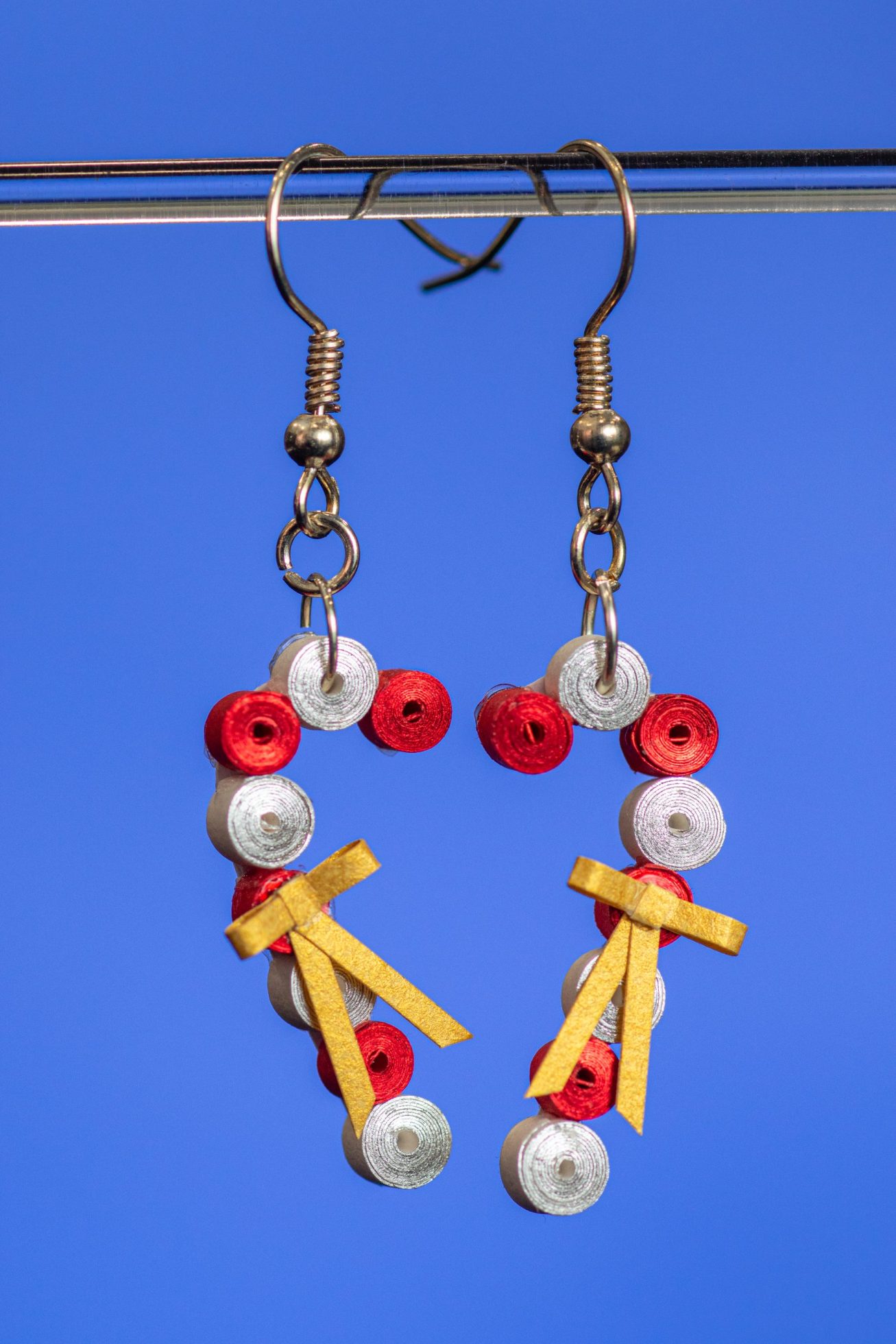 These earrings made with 1/8″ white paper with silver gilding on one edge and red paper with red gilding on one edge that gives these earrings a shimmer. They have a tiny bow made of gold paper.