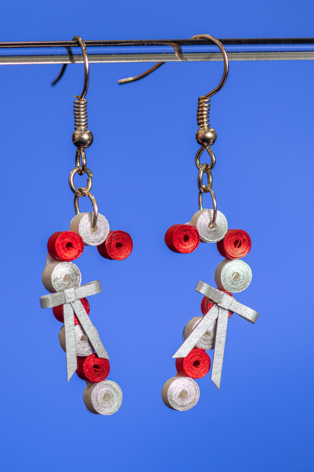 These earrings made with 1/8″ white paper with silver gilding on one edge and red paper with red gilding on one edge that gives these earrings a shimmer. They have a tiny bow made of silver shimmer paper.